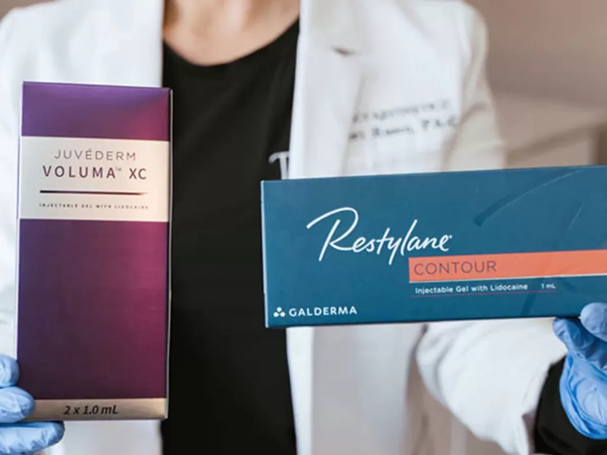 female provider holding packages of Juvederm Voluma XC and Restylane Contour