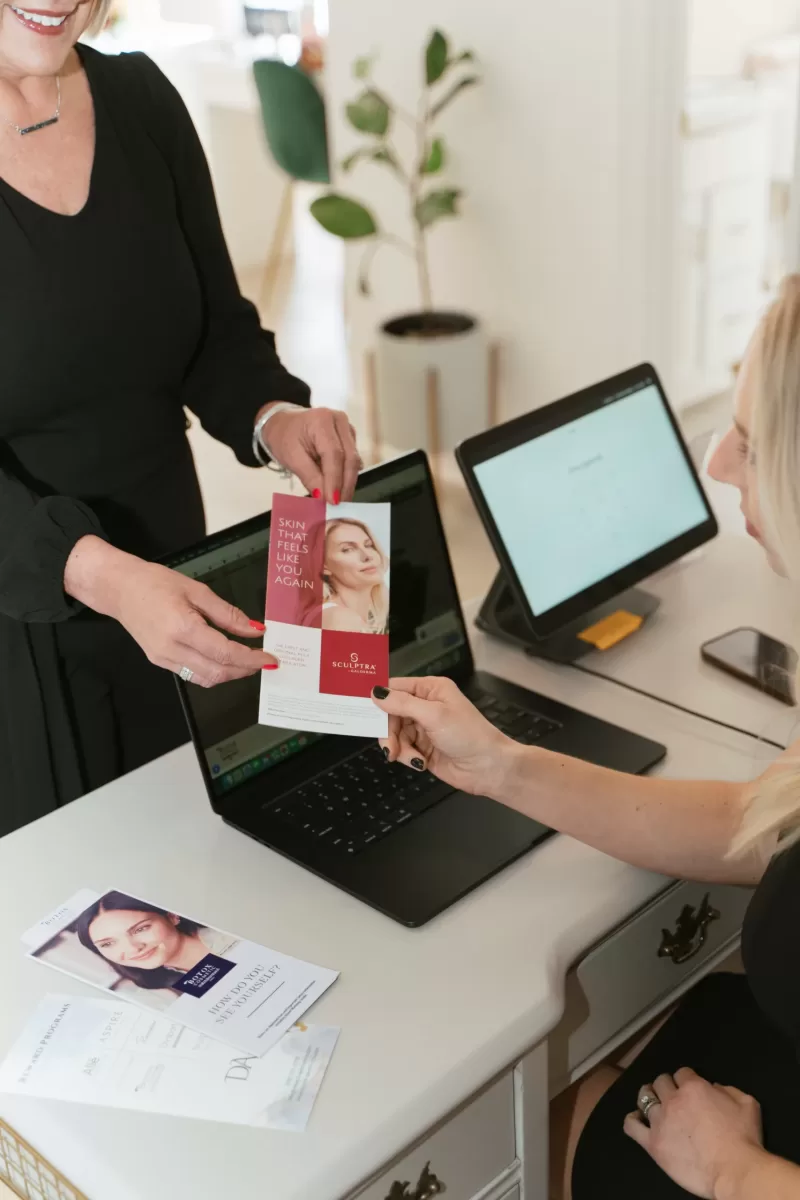 Emily handing a patient a brochure with Sulptra FAQs